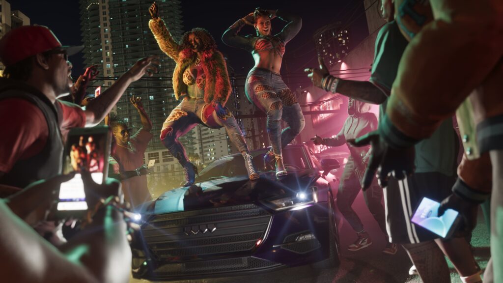 GTA 6 a crowd of men surround two women dancing on top of a car in the middle of the city